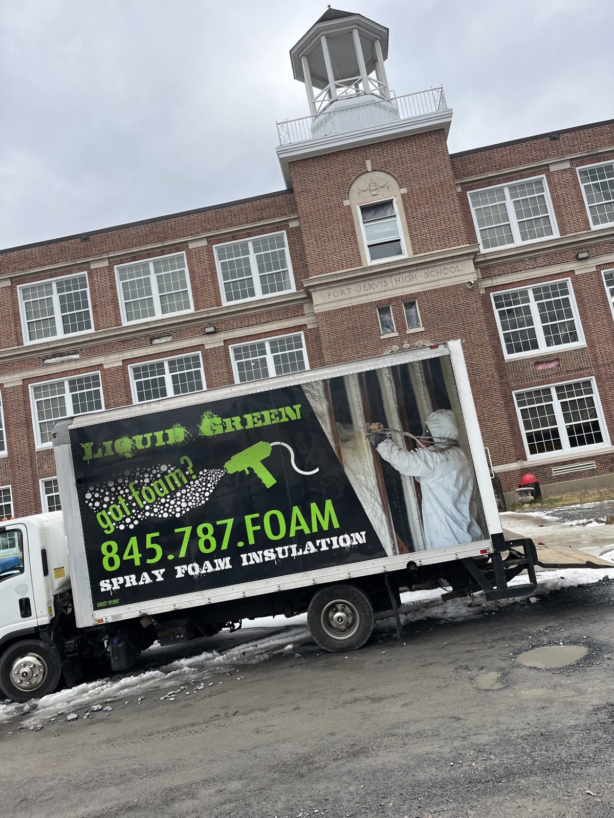 Liquid Green franchise — worker spraying foam on the truck wrap